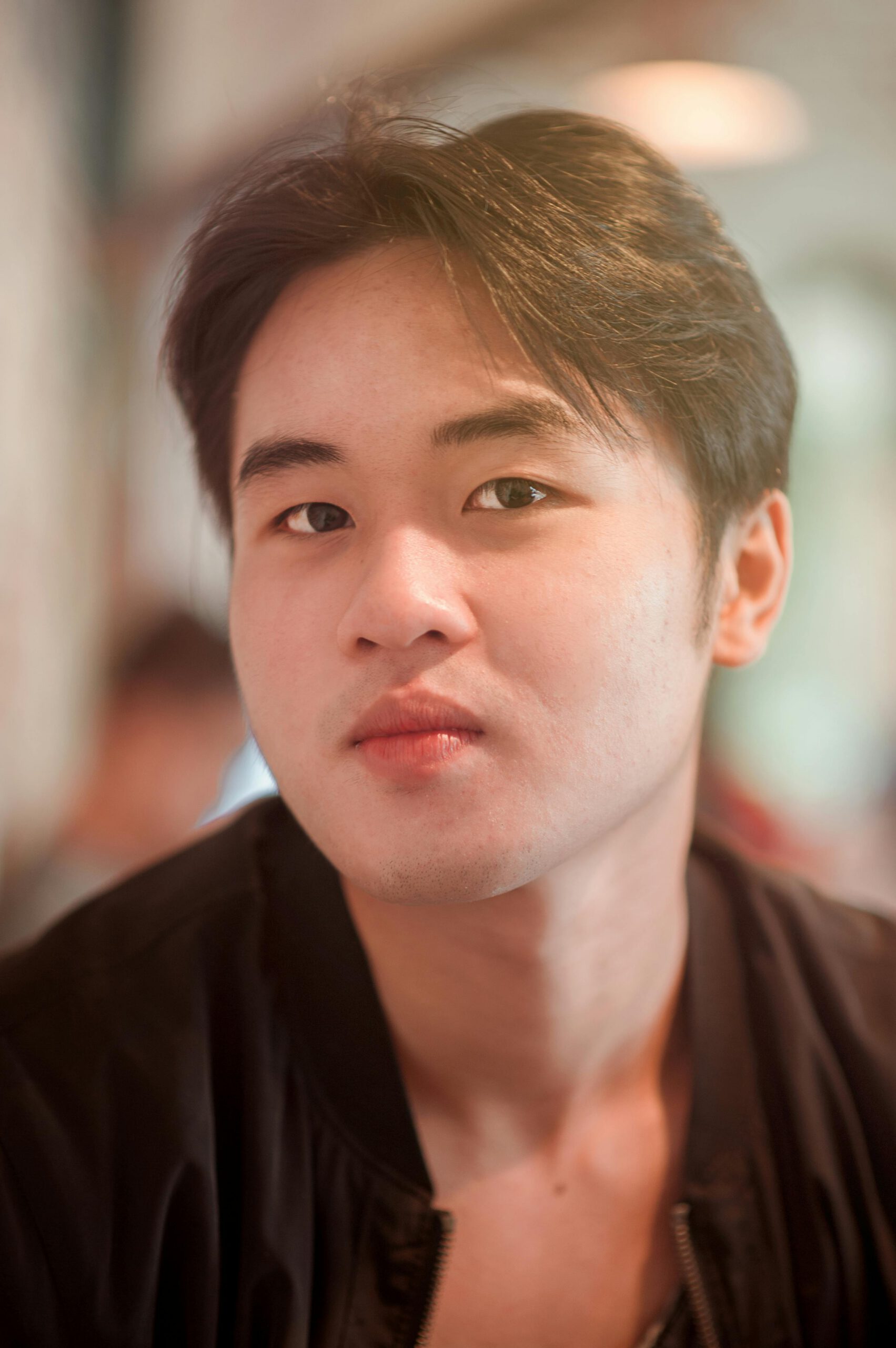 Close-up portrait of a young man indoors, capturing a thoughtful expression in soft lighting.
